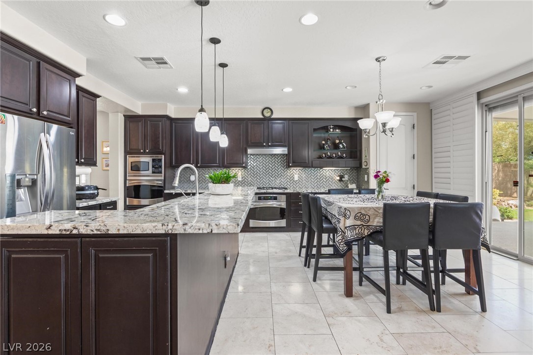 8431 Durango Ranch Court Las Vegas, NV 89113 - Photo 10 of 49 This kitchen showcases stylish dark cabinetry, sparkling granite counters, and modern stainless steel appliances.