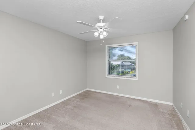 an empty room with a window and a fan