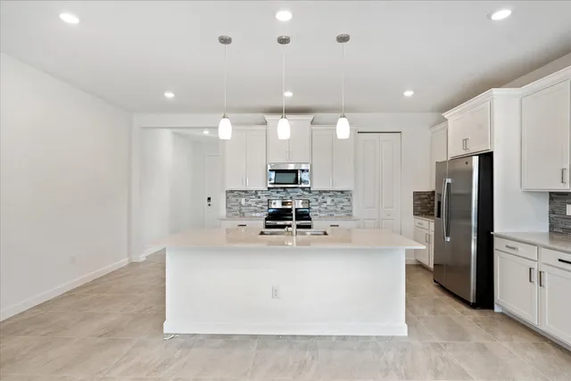a kitchen with kitchen island a stove a refrigerator and a sink