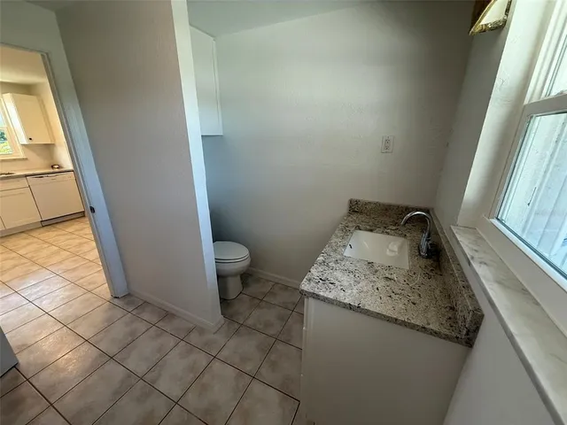 a bathroom with a granite countertop sink and a toilet