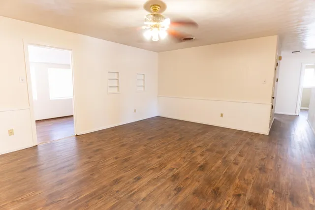 a view of empty room with wooden floor and ceiling fan