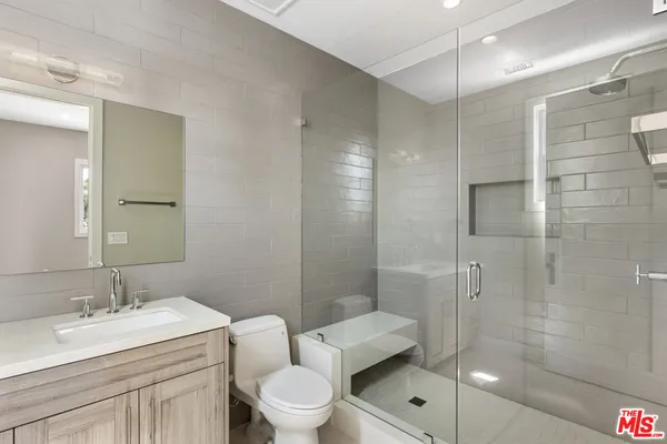 a bathroom with a toilet a sink a mirror and shower