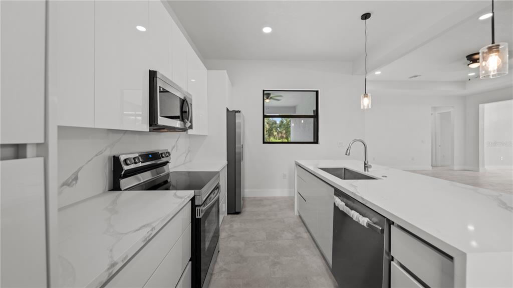 9 Tee View Road Rotonda West, FL 33947 - Photo 20 of 38 a kitchen that has a sink a stove and a microwave oven with wooden floor