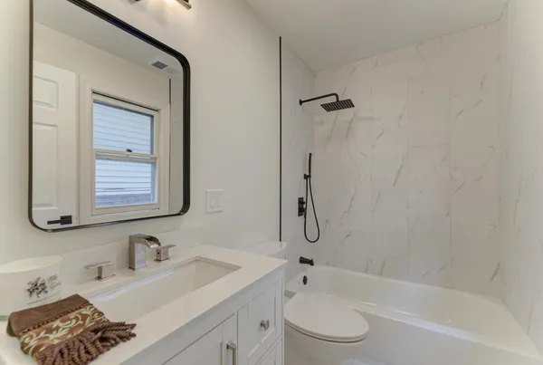 a bathroom with a bathtub shower sink vanity and toilet