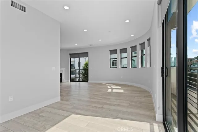 a view of an empty room with window and wooden floor