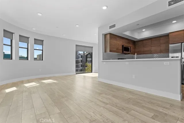 a view of a kitchen with kitchen island a sink wooden floor and an empty room