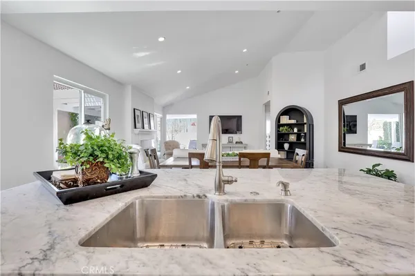 a kitchen with stainless steel appliances kitchen island granite countertop a refrigerator a stove a sink a oven and white cabinets