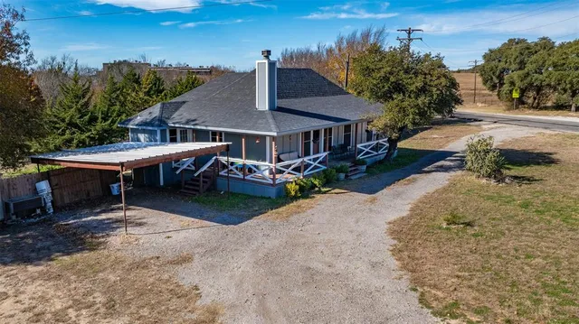 an aerial view of a house with garden space and trees all around