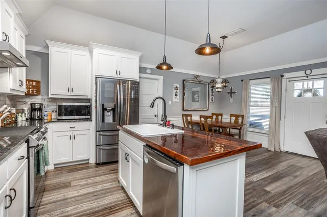 a kitchen with stainless steel appliances granite countertop a sink a stove and a refrigerator