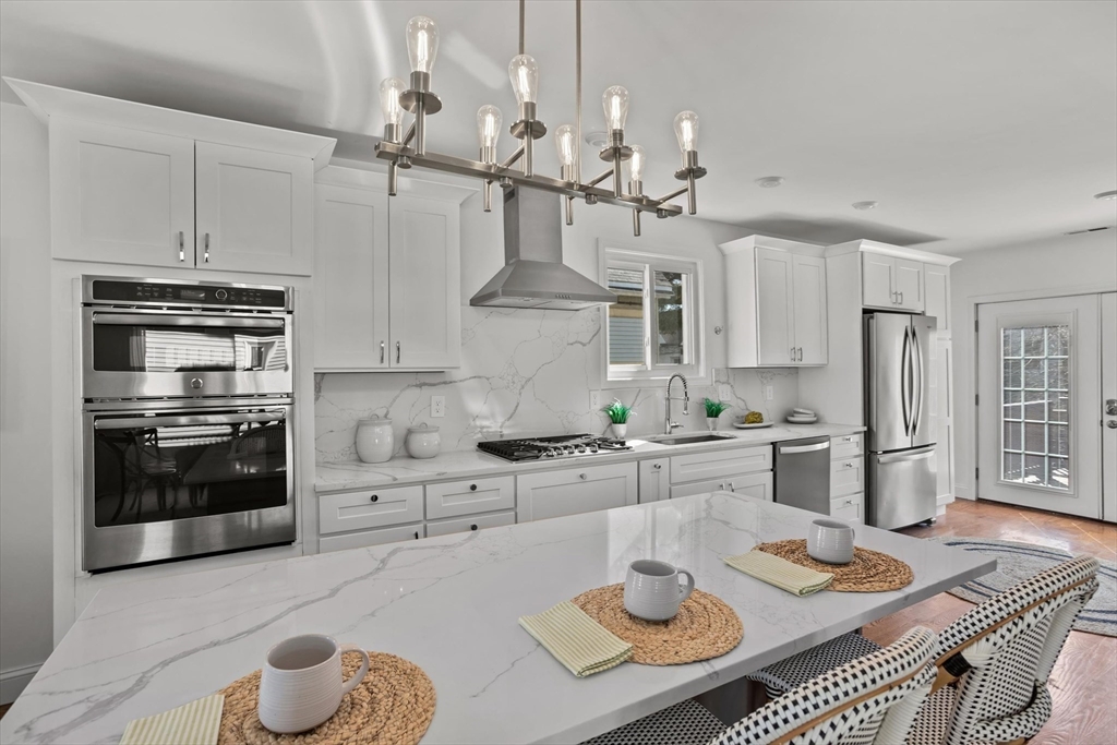 a kitchen with stainless steel appliances kitchen island granite countertop a stove and white cabinets
