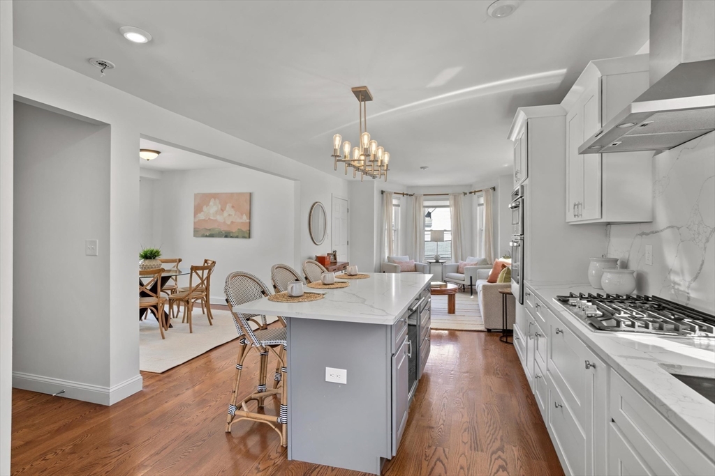 98 Flint Street, Unit 2 Somerville, MA 02145 - Photo 3 of 40 a very nice looking kitchen with granite countertop a stove top oven a sink a dining table and chairs with wooden floor