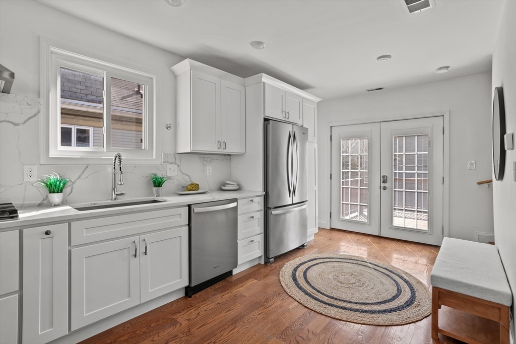98 Flint Street, Unit 2 Somerville, MA 02145 - Photo 5 of 40 a kitchen with stainless steel appliances a stove a refrigerator and a sink with wooden cabinets