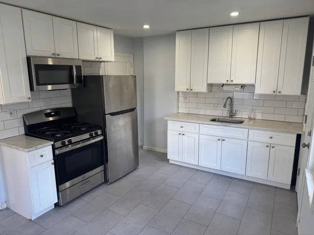 a kitchen with granite countertop white cabinets and stainless steel appliances