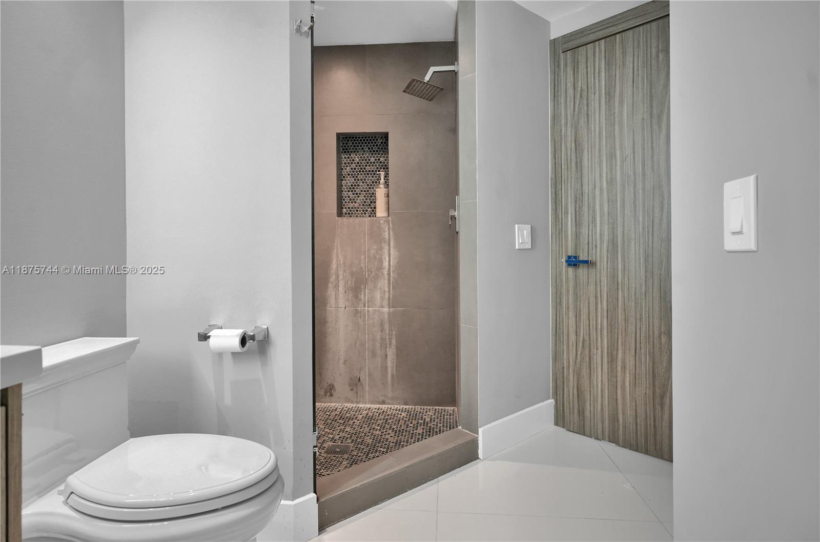 4779 Collins Avenue, Unit 1805 Miami Beach, FL 33140 - Photo 35 of 39 a bathroom with a granite countertop toilet and a shower