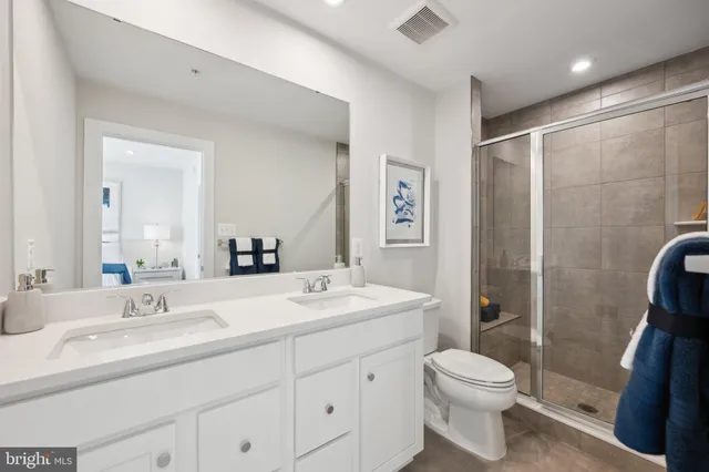 a bathroom with a toilet a sink a mirror a shower a vanity and window