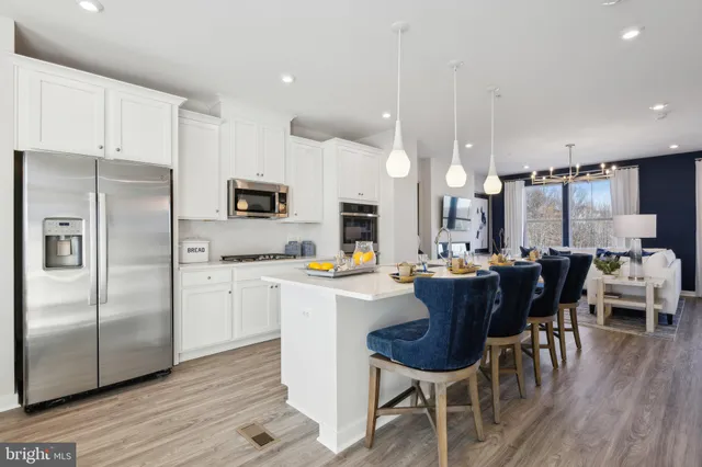 a kitchen with stainless steel appliances a dining table chairs stove and refrigerator