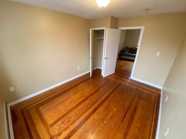 a view of an empty room with wooden floor and stairs