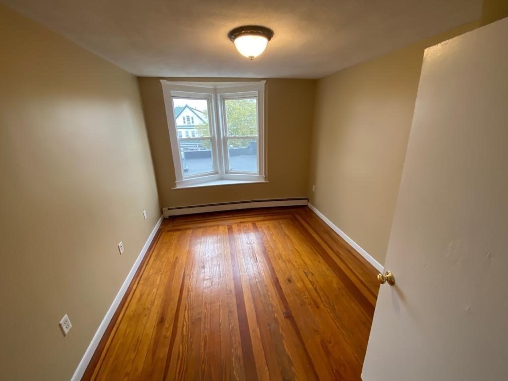 5 Lowden Avenue, Unit 2 Somerville, MA 02144 - Photo 7 of 20 an empty room with wooden floor and windows