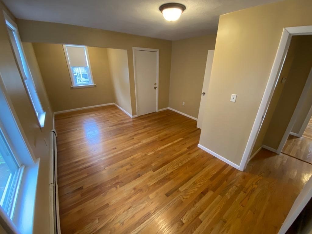 5 Lowden Avenue, Unit 2 Somerville, MA 02144 - Photo 8 of 20 an empty room with wooden floor and windows