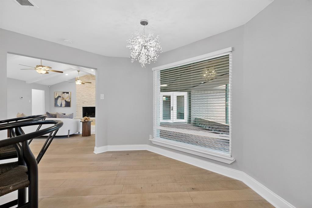 7631 Meadow Road Dallas, TX 75230 - Photo 10 of 40 A bright breakfast room featuring a chandelier and a tall, wide window with a view to the patio at the back.