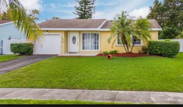 a view of a house with a yard and palm trees