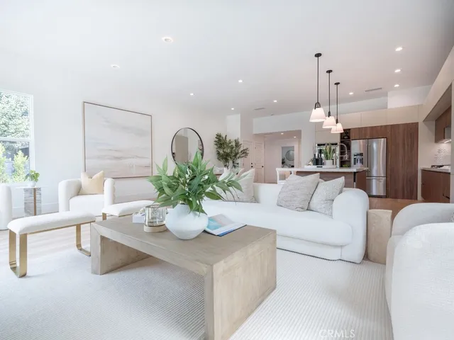 a living room with couches and kitchen view with wooden floor