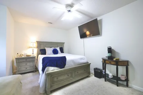 a bedroom with a bed and a flat tv screen on dresser