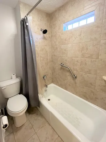 a white toilet sitting next to a bath tub and a shower