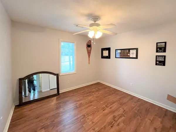 a view of an empty room with window and wooden floor
