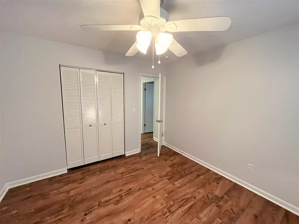 an empty room with wooden floor fan and window