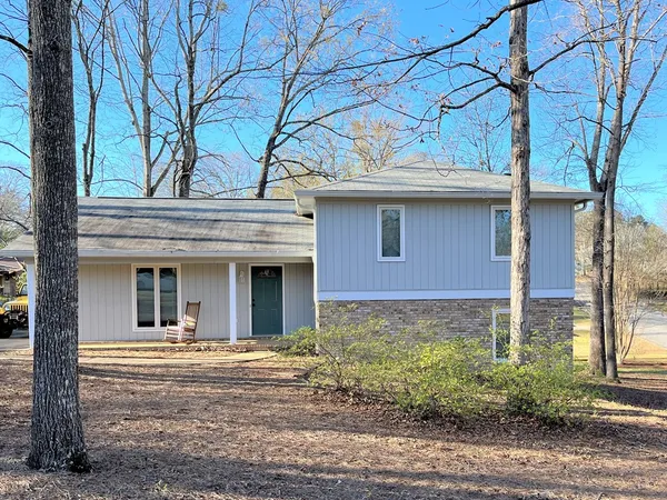 a view of a house with a small yard plants and large tree