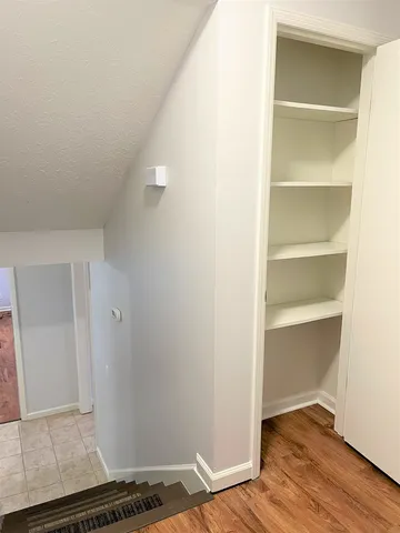 a view of an empty room with wooden floor and closet