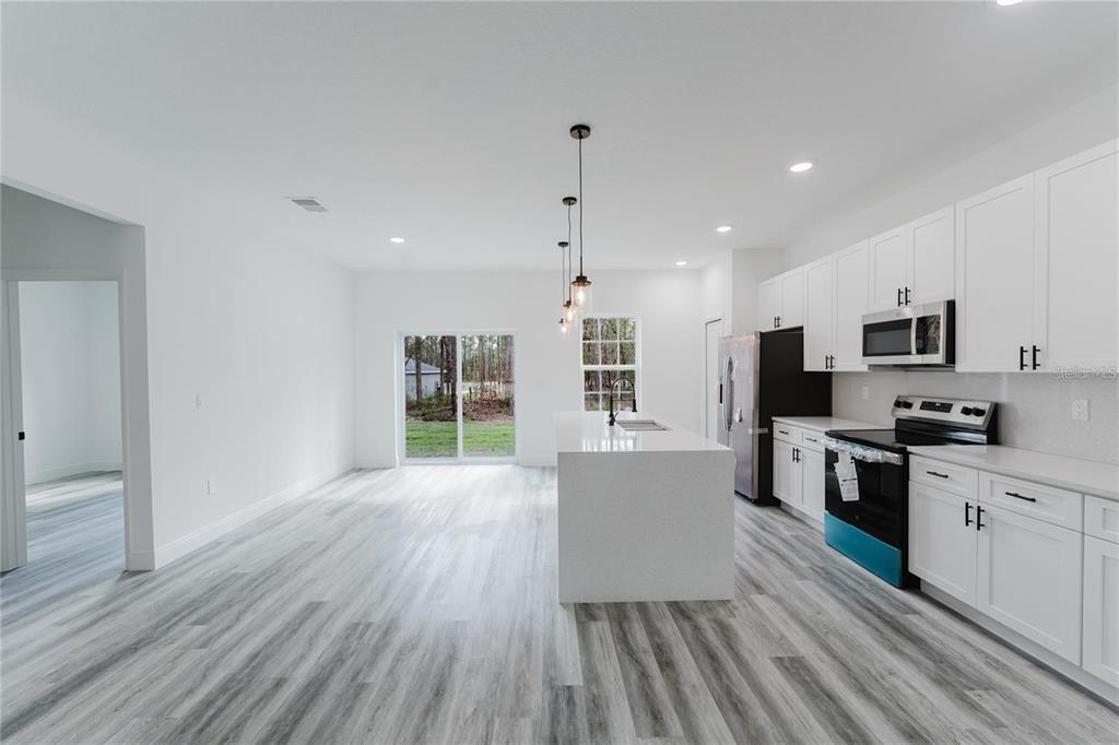 6732 Southwest 132nd Street Ocala, FL 34473 - Photo 8 of 36 a large kitchen with kitchen island a stove a sink dishwasher a refrigerator white cabinets with wooden floor