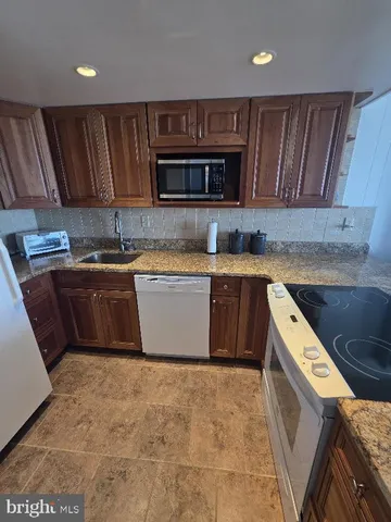 a kitchen with stainless steel appliances granite countertop wooden cabinets a sink a stove a refrigerator and island
