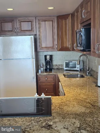 a kitchen with kitchen island granite countertop a sink and a stove top oven