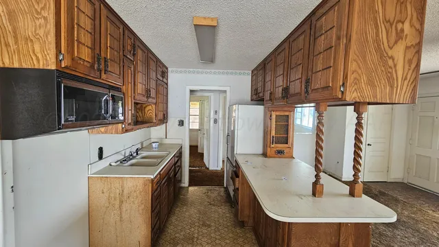 a kitchen with stainless steel appliances granite countertop a refrigerator a stove and a sink with wooden floor