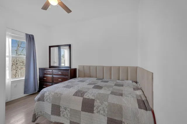 a bed sitting in a bedroom next to a window with wooden floor
