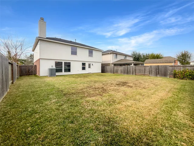a white house that has a big yard with plants and trees with wooden fence