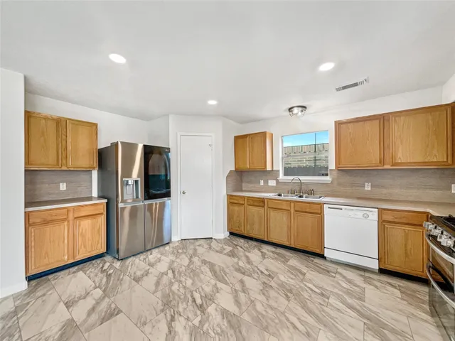 a large kitchen with stainless steel appliances granite countertop a refrigerator a sink dishwasher a oven with large countertops and wooden floor