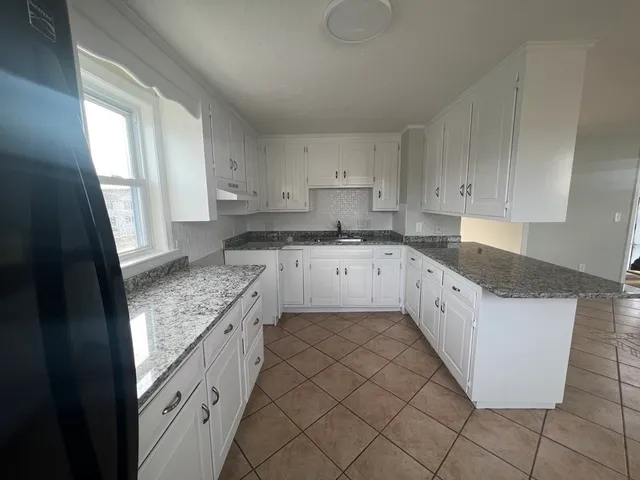 a kitchen with granite countertop cabinets sink and a stove