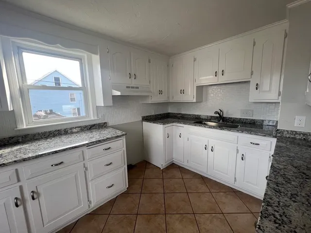 a kitchen with granite countertop white cabinets and white appliances