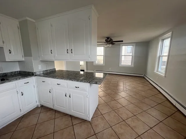 a kitchen with granite countertop white cabinets and window