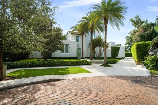 a front view of a house with a yard and palm trees