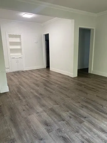 a view of an empty room with wooden floor and closet