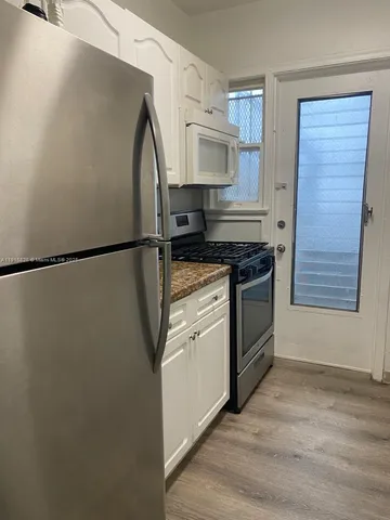 a kitchen with stainless steel appliances a refrigerator sink and white cabinets
