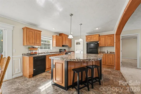 a kitchen with stainless steel appliances granite countertop a stove top oven a sink a dining table and chairs