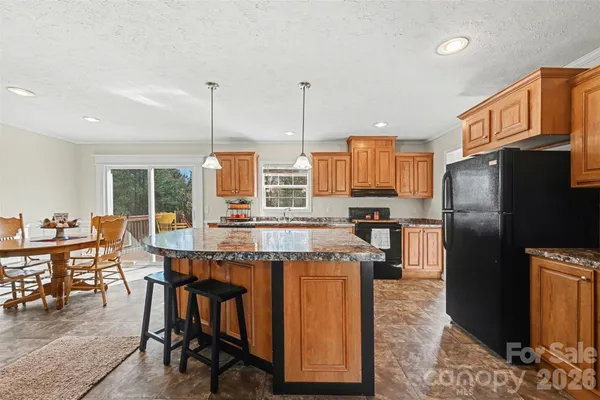 a kitchen with stainless steel appliances granite countertop a stove refrigerator and chairs