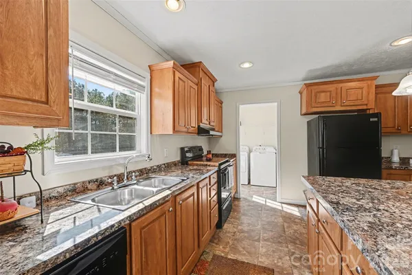 a kitchen with granite countertop a sink stove and refrigerator