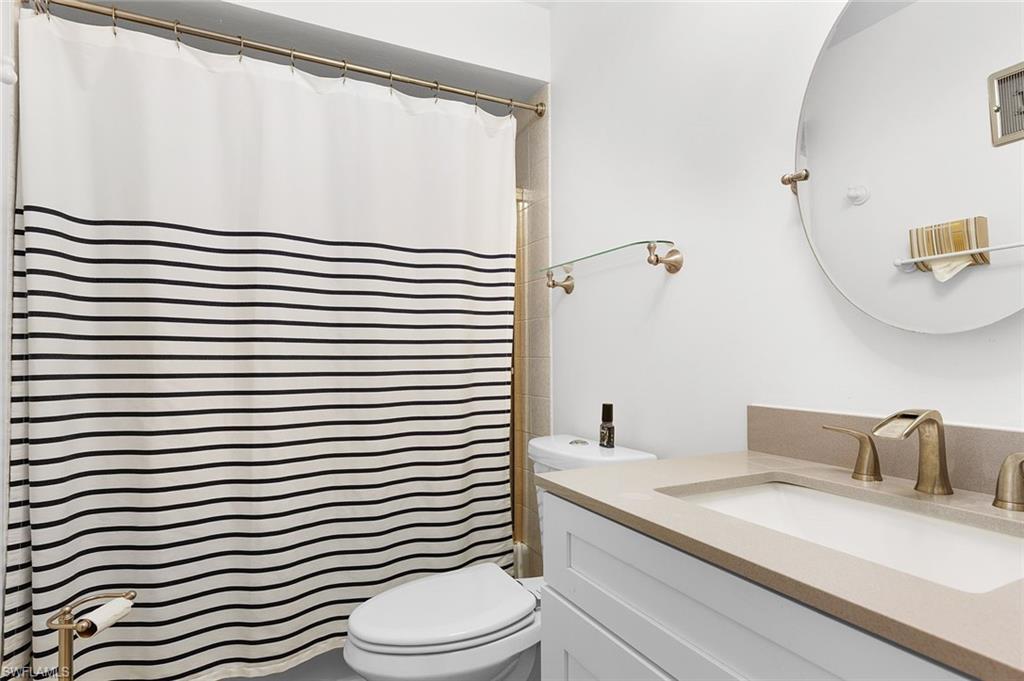 3360 10th Street North, Unit 1210 Naples, FL 34103 - Photo 20 of 28 a bathroom with a sink a toilet and shower curtain