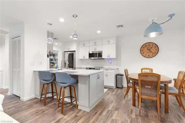 a kitchen with a table chairs a sink dishwasher stove and cabinets with wooden floor